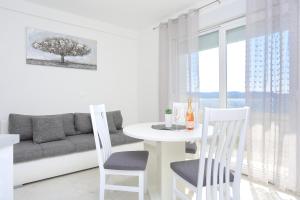 a living room with a table and chairs and a couch at Family friendly apartments with a swimming pool Zivogosce - Porat, Makarska - 18150 in Živogošće