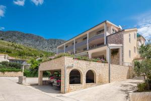 a large building with flowers on top of it at Apartments and rooms by the sea Duce, Omis - 18155 in Omiš
