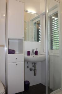 a white bathroom with a sink and a shower at Family friendly house with a swimming pool Bisko, Zagora - 18181 in Dicmo