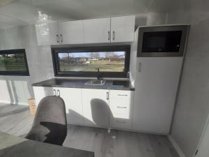 eine Küche mit weißen Schränken, einem Waschbecken und einem Fenster in der Unterkunft Hausboote Unteres Odertal Hausboot Seeadler in Schwedt