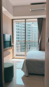 een slaapkamer met een bed en een groot raam bij Cozy Studio Suite in Taman Anggrek Residences in Jakarta