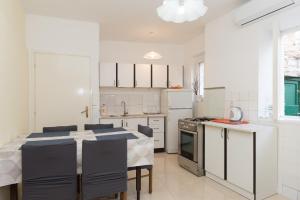 a white kitchen with a table and chairs in it at Apartments by the sea Krapanj, Sibenik - 18180 in Šibenik