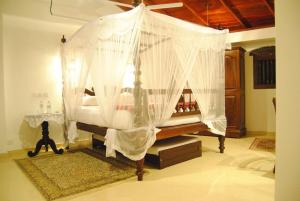 a canopy bed with white curtains in a room at La Veranda Di Serena in Unawatuna