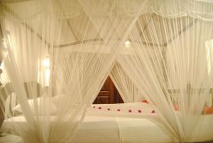 a bed with white mosquito netting on it at La Veranda Di Serena in Unawatuna