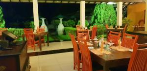 a dining room with tables and chairs and a garden at Flower Garden Lake Resort in Tissamaharama