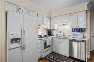 uma cozinha com armários brancos e um frigorífico em Southwinds C8 em Atlantic Beach