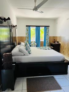 a bedroom with a large bed with blue curtains at Cap Jean Marie Beach Villas in Anse Kerlan