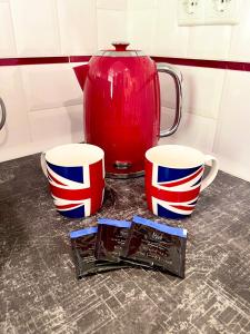 two coffee cups and a vase on a counter at Apartment Studio London 2 in Irpin'