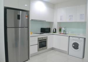 a white kitchen with a refrigerator and a dishwasher at Studio at The Ridge KL East W in Kuala Lumpur