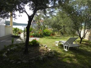 ein weißer Stuhl im Gras unter einem Baum in der Unterkunft Apartments by the sea Kampor, Rab - 18268 in Rab