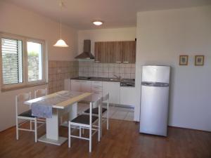 eine Küche mit einem Kühlschrank sowie einem Tisch und Stühlen in der Unterkunft Apartments by the sea Kampor, Rab - 18268 in Rab