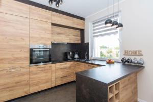 a kitchen with wooden cabinets and a black counter top at Carmel Rentyear Apartments in Gdańsk