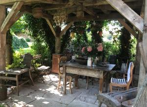 een tafel en stoelen onder een houten pergola bij La Ferme de Marie in Rangen