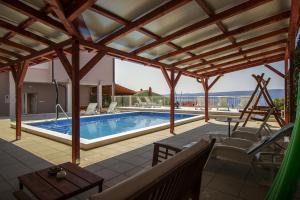 a patio with a swimming pool and a wooden pergola at Apartments and rooms with a swimming pool Lokva Rogoznica, Omis - 18328 in Lokva Rogoznica