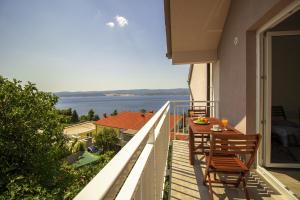 a balcony with a table and chairs and a view of the water at Apartments and rooms with a swimming pool Lokva Rogoznica, Omis - 18328 in Lokva Rogoznica