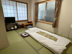 a bedroom with a bed in a room with a window at Ryokan Mikawaya in Tokyo