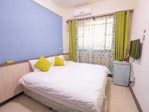 a bedroom with a bed with yellow pillows and a window at Jin Da Paint B&B in Jinning