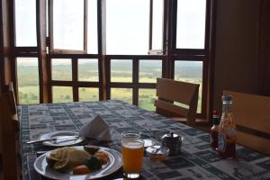 a table with a plate of food and a glass of orange juice at Rift Valley Game Lodge Rubirizi in Katara