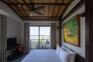 a bedroom with a bed with a ceiling fan at Nghê Prana Hotel & Spa Hoi An in Hoi An