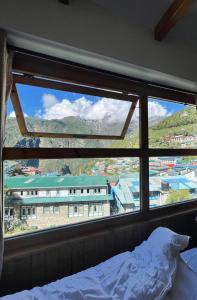 a bedroom with a view of a building through a window at Hotel Camp de Base in Namche
