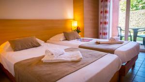 - 2 lits dans une chambre d'hôtel avec des serviettes dans l'établissement Village Club L'Oustal Del Mar, au Lavandou