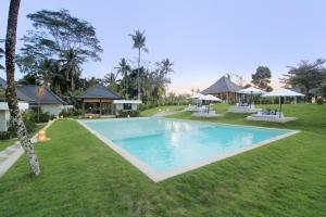 ein Schwimmbad in der Mitte eines Grasfeldes in der Unterkunft Puri Hijau Villa with Jungle View in Tegalalang Ubud in Ubud