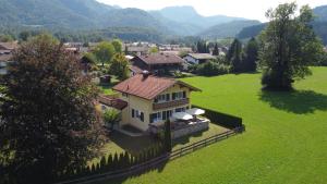 a house in a green field with mountains in the background at Villa am Bach in Unterwössen
