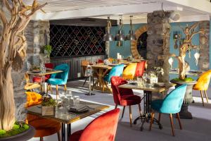 um restaurante com cadeiras e mesas coloridas numa sala em Hôtel Courcheneige em Courchevel