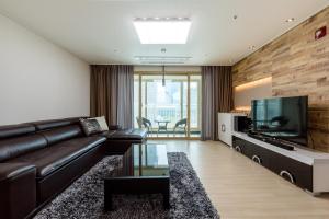 a living room with a black leather couch and a flat screen tv at JS Residence Hotel Okpo in Geoje 