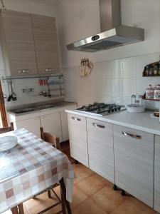 cocina con armarios blancos, mesa y fogones en Casa vacanze Tuoro, en Tuoro sul Trasimeno