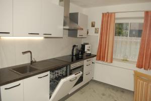 een keuken met witte kasten, een wastafel en een raam bij Ferienwohnung bon WAB in Hallstatt