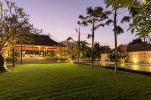 a lawn in front of a building with palm trees at Villa Nusantara in Sanur