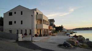 duży biały budynek obok zbiornika wodnego w obiekcie Apartments by the sea Simuni, Pag - 18386 w mieście Kolan