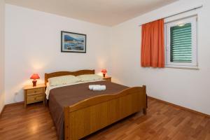 1 dormitorio con cama y ventana en Apartments by the sea Seget Vranjica, Trogir - 18229, en Seget Vranjica