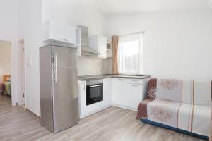 a small kitchen with a refrigerator and a couch at Apartments with a parking space Split - 18214 in Solin