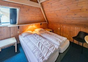1 dormitorio con 1 cama en una habitación de madera en Terschelling Natuurlijk, en Kinnum
