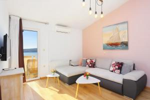 een woonkamer met een bank en een tv bij Apartments by the sea Seget Donji, Trogir - 18488 in Trogir