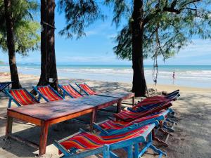 un grupo de sillas y una mesa de madera en la playa en Rayong Condo Chain studio room en Ban Pak Khlong Phe