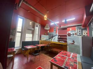 um restaurante com duas mesas e uma cozinha com paredes vermelhas em Oliwka Hostel em Varsóvia