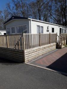 a house with a wooden fence in front of it at Camelot Holiday Park, Longtown, Tranquility 21 Coworth in Carlisle