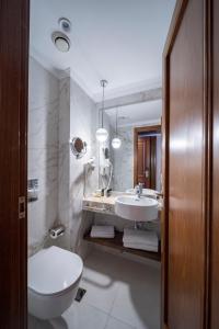 a bathroom with a sink and a toilet and a mirror at Electra Palace Athens in Athens