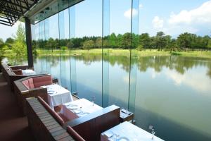 un restaurante con vistas a un lago con mesas y sillas en The Prince Karuizawa, en Karuizawa