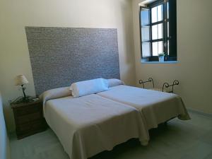 1 cama en un dormitorio con pared de ladrillo en Estación de Coripe, en Coripe