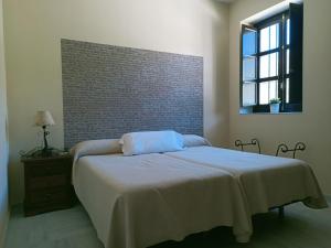 Un dormitorio con una cama y una pared de ladrillo. en Estación de Coripe, en Coripe
