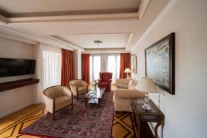 sala de estar con sofá, sillas y TV en Electra Palace Athens, en Atenas