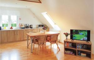 a kitchen with a table with chairs and a television at Cozy Home In Grzybowo With Kitchenette in Grzybowo