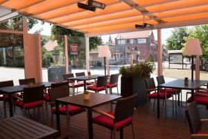 un patio al aire libre con mesas y sillas y una calle en Komforthotel Kaiserhof en Kelbra