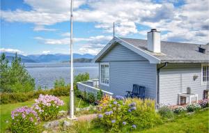 a house with flowers in front of a body of water at Beach Front Home In Jondal With House Sea View in Jondal