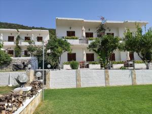 a white building with trees in front of a yard at Theasea in Parga
