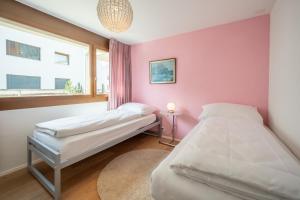 1 dormitorio con 2 camas y pared de color rosa en LAAX Homes - Casa Lanezzi 3, en Flims